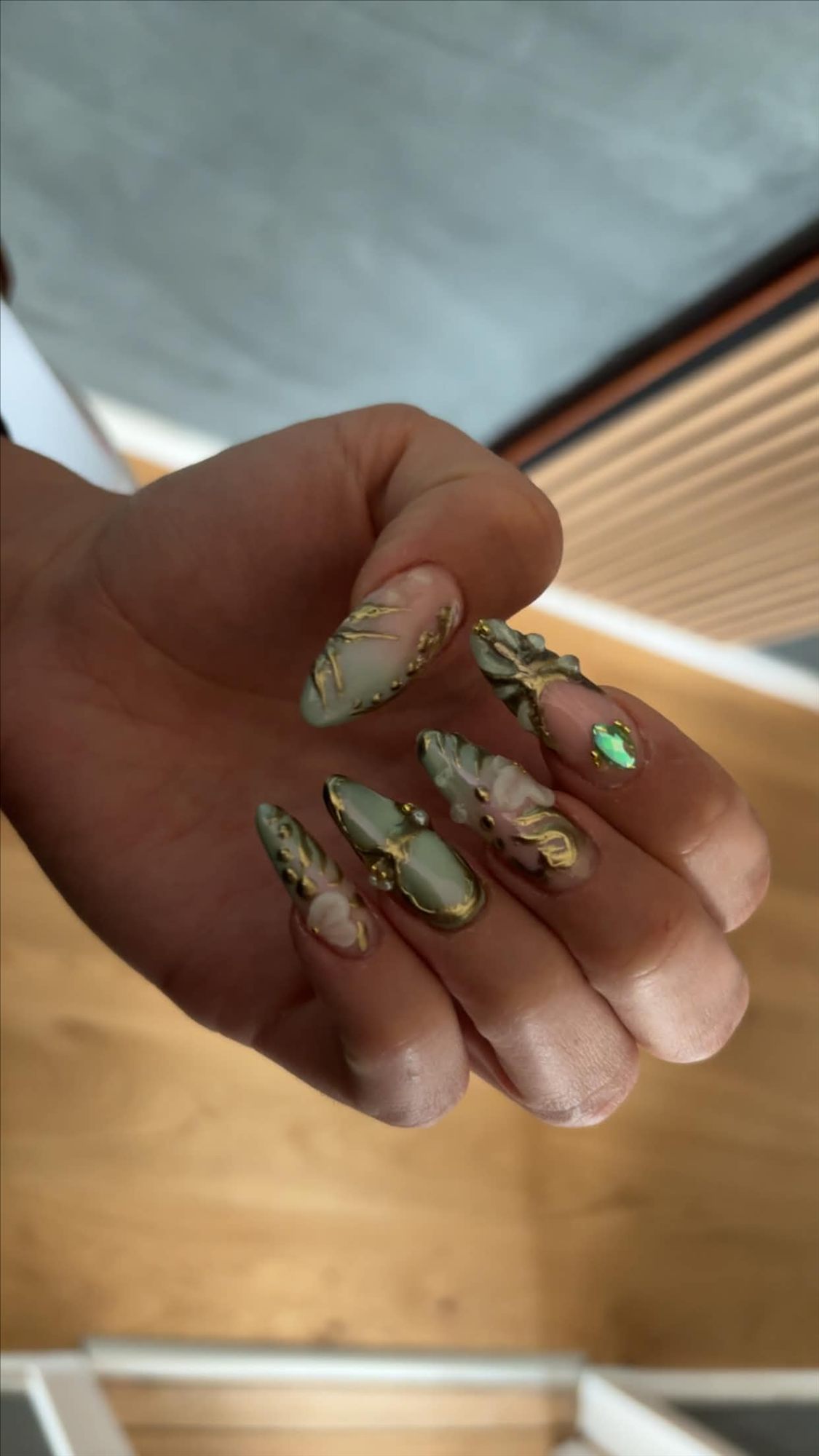 Detaljeret nail art med salviegrøn, blomster og guld